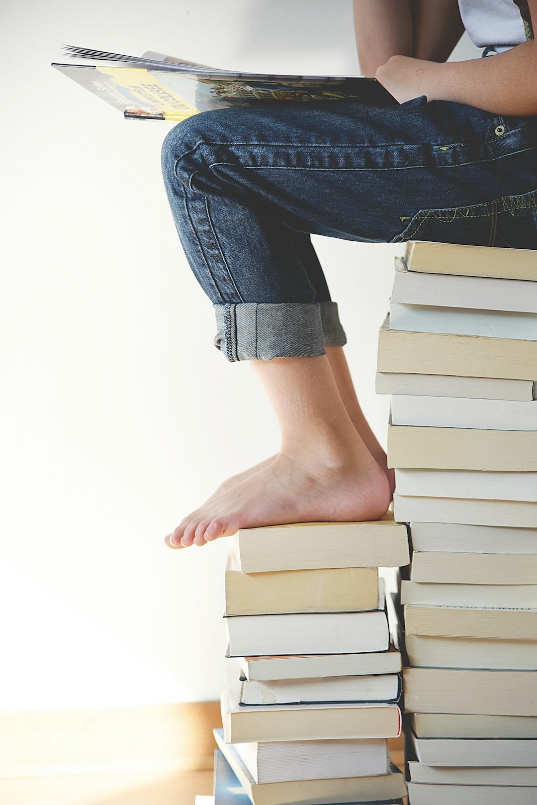 person-sitting-on-stack-of-books-while-reading-l8snwgunqbu